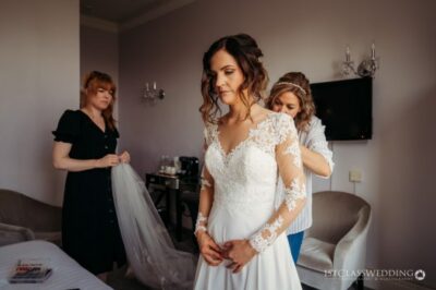 Bride getting ready with helpers on wedding day.