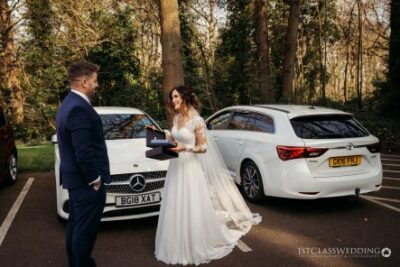 Bride and groom with luxury cars at wedding.