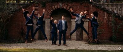 Groomsmen jumping joyfully at a wedding venue.