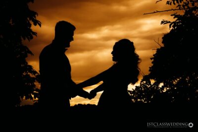 Couple's silhouette against sunset sky.