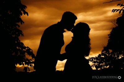 Silhouette of couple kissing at sunset.