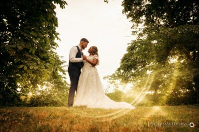 Couple embracing at sunset in wedding attire.
