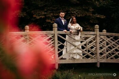 Bride and groom posing on a garden bridge