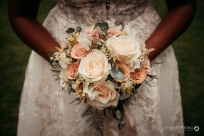 Bride holding peach and cream rose bouquet.