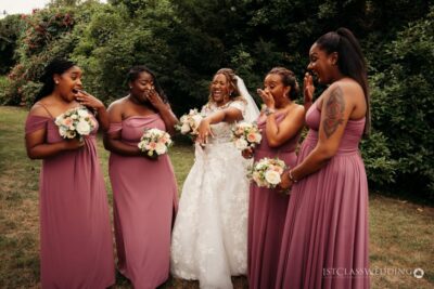 Joyful bride with bridesmaids laughing outdoors.
