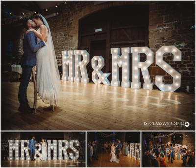 Bride and groom with illuminated "MR & MRS" sign at wedding.