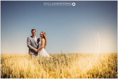 Couple posing in sunny wheat field.
