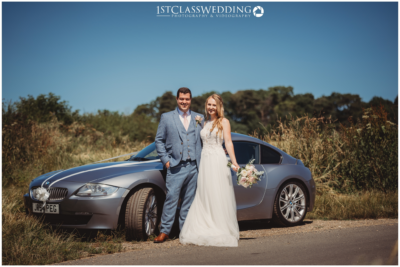 Couple with car on wedding day.