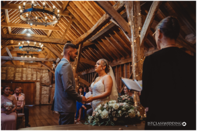 Couple exchanging vows in rustic barn wedding venue.