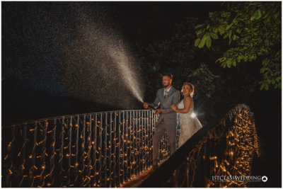 Couple with sparkler on bridge at night wedding.