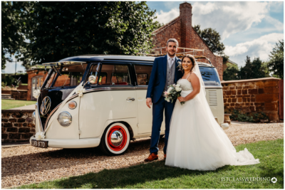 Bride and groom with vintage Volkswagen van at wedding.