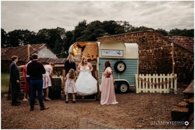 Outdoor wedding party by vintage photo booth caravan.