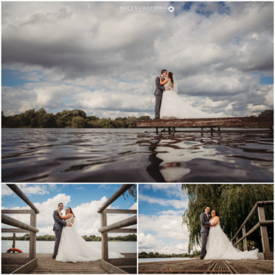 Couple embracing on lakeside dock, cloudy sky, wedding photography.
