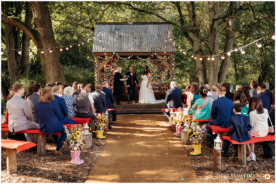 Outdoor wedding ceremony with guests and string lights.