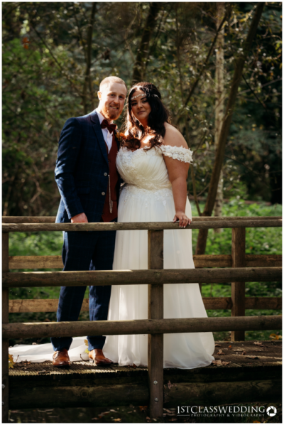 Couple in wedding attire on wooden bridge outdoors