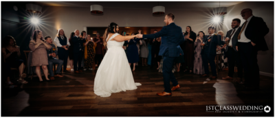Wedding couple's first dance with guests watching.
