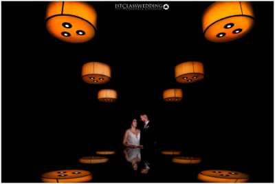 Couple under orange lamp lights, dark ambiance, reflection.