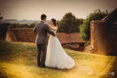 Bride and groom sharing moment in countryside sunset.