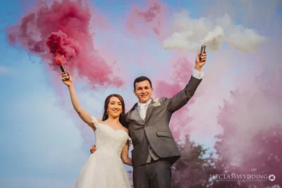 Bride and groom with smoke flares celebrating wedding.