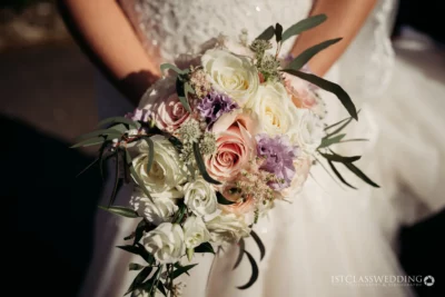 Bride holding pastel wedding bouquet.