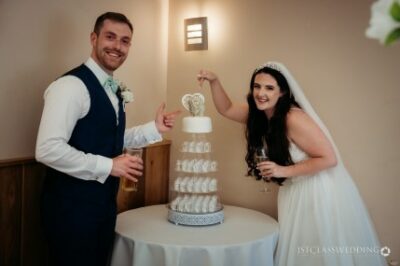 Bride and groom posing with wedding cake.