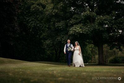 Couple walking in park on wedding day.
