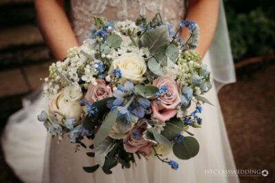 Bride holding blue and white wedding bouquet.