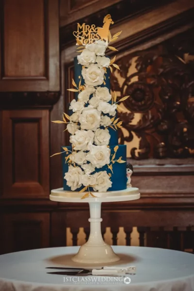 Elegant wedding cake with white roses and blue tiers.
