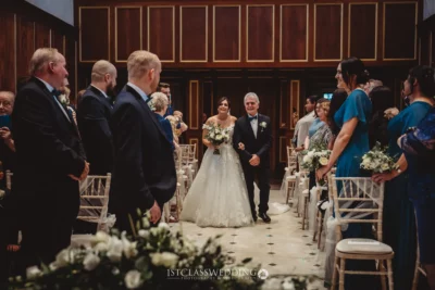 Bride walking aisle with father at wedding ceremony