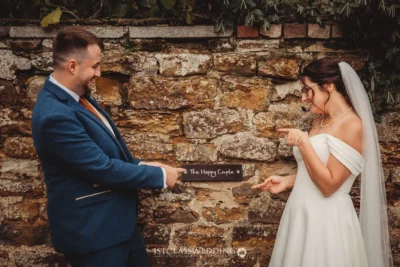 Bride and groom jokingly point at sign "The Happy Couple