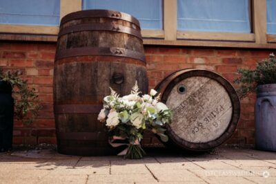 Wooden barrels and bridal bouquet outside a rustic venue.