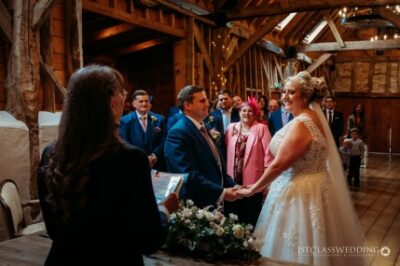 Couple exchanging vows at rustic barn wedding ceremony.