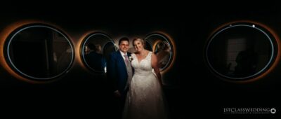 Bride and groom smiling in stylish circular light setting.