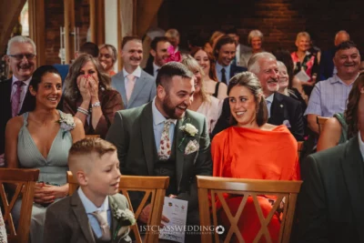 Joyful wedding guests laughing during ceremony.