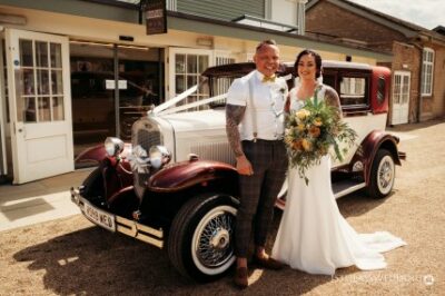 Couple with vintage car on wedding day.
