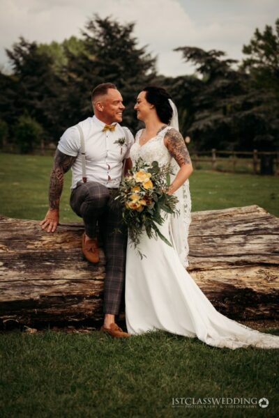 Tattooed couple smiling on wedding day outdoors.