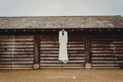Bridal dress hanging on rustic wooden barn exterior.