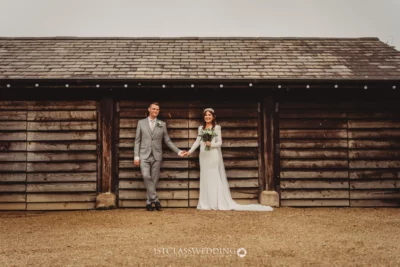 Bride and groom holding hands outside wooden barn.