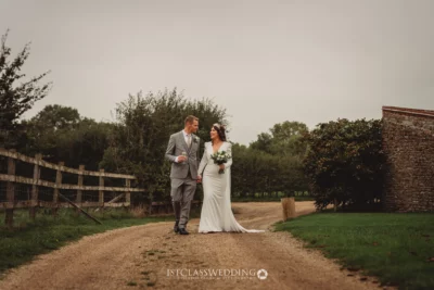 Bride and groom walking on country path after wedding