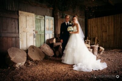 Bride and groom posing in rustic barn setting.