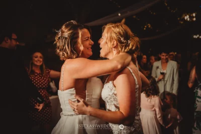 Two women joyfully dancing at a wedding reception.