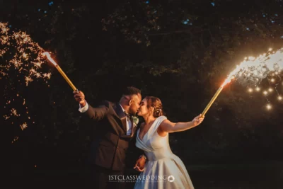 Couple kissing with sparklers at night wedding.