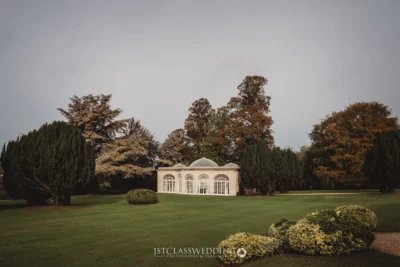 Elegant conservatory in serene English garden setting.