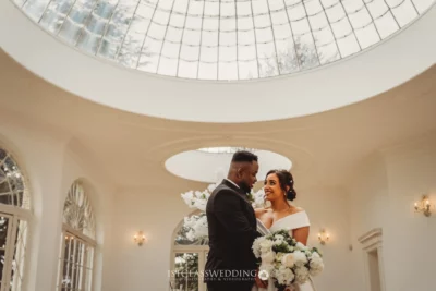 Couple exchanging vows under elegant dome skylight.