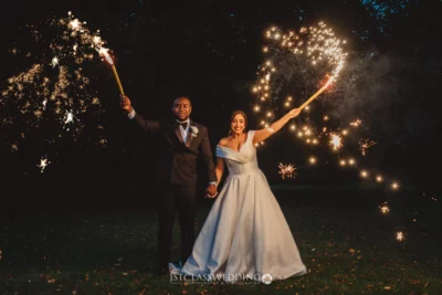 Bride and groom celebrating with sparklers at night.
