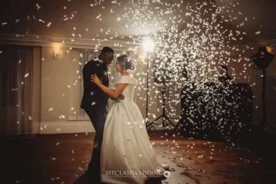 Couple dancing amidst confetti shower at wedding.