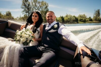 Bride and groom on boat, sunny wedding day.