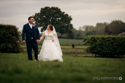 Bride and groom holding hands in a field.