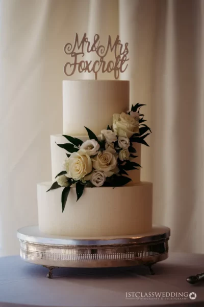 Elegant wedding cake with "Mr & Mrs" topper and flowers.