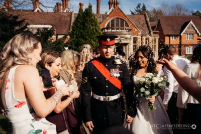 Bride and groom in uniform at sunny UK wedding.
